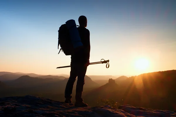 Sharp silhouette of a tall man on the top of the mountain with sun in the frame. Tourist guide in mountains — Stock Photo, Image