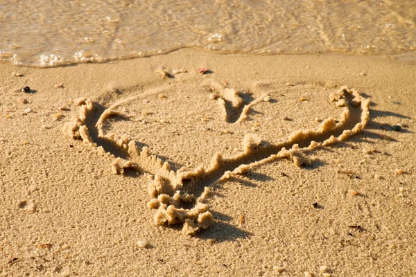 Прекрасное маленькое сердце, зарисованное соленым песком на пляже. Вечерние теплые тона заката . — стоковое фото