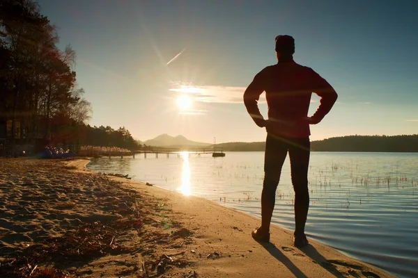 Silhouette of tall sportsman on decline seeing over bay to sun — Stock Photo, Image