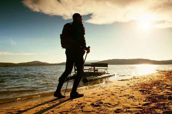 Touriste sur la plage à vieux pédalo. Homme avec des bâtons en vêtements sportifs chauds au coucher du soleil. Météo d'automne . — Photo