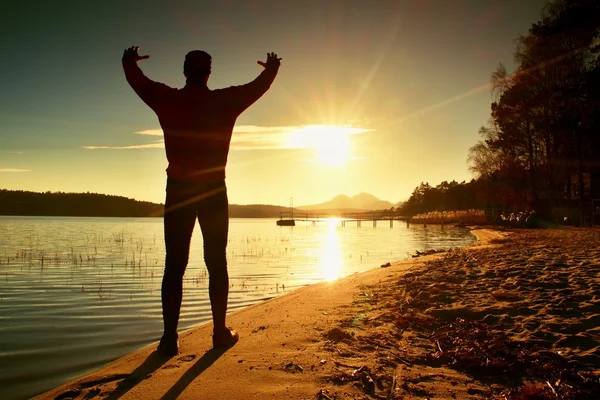 Lång man. Solnedgången över ön och kajen vid kusten. Varma färger och nyanser av den uppgående solen — Stockfoto