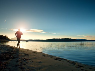 Çalışan adam. Erkek koşucu gündoğumu sırasında kumsalda koşu