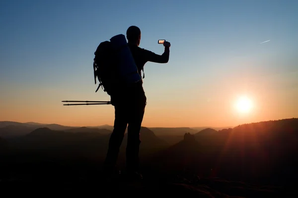 Starker Mann Wanderer beim Fotografieren mit Smartphone auf dem Gipfel des Berges. Tagesanbruch am Horizont — Stockfoto