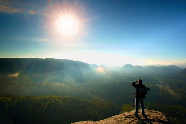 Turist med ryggsäck och polacker på rocky peak. Solig dag, drömmande fogy dalen nedanför — Stockfoto