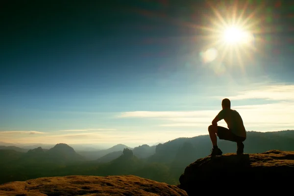 Samotnie turysta w czarne spodnie stanąć na skale imperium i oglądanie nad doliną mgliste i mgliste rano słońce. — Zdjęcie stockowe