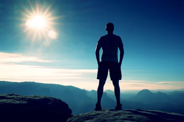 Slim turista sul picco tagliente di roccia nel parco imperi rocciosi sta guardando sopra la nebbiosa e nebbiosa valle del mattino al sole — Foto Stock