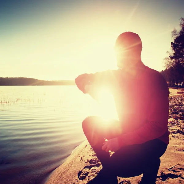 Man athlete checking time during workout run exercise outdoors at ocean beach in sunny cold morning — Stock Photo, Image