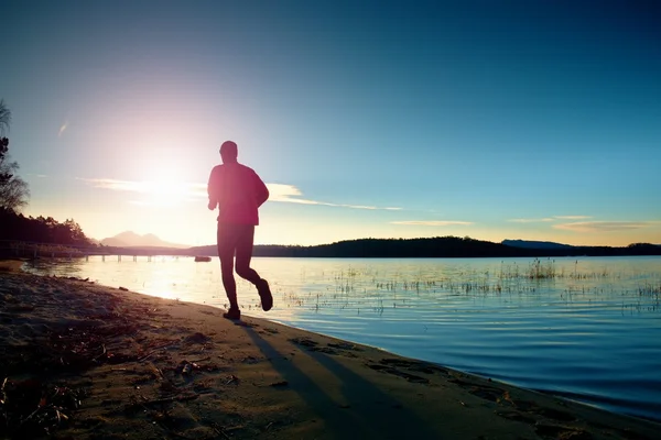 Sportsman courir à l'incroyable coucher de soleil d'été à la plage dans le sport et mode de vie sain concept — Photo