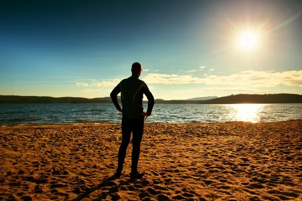 Silhouet van persoon in sportkleding en korte haren op strand zien in zon boven zee — Stockfoto