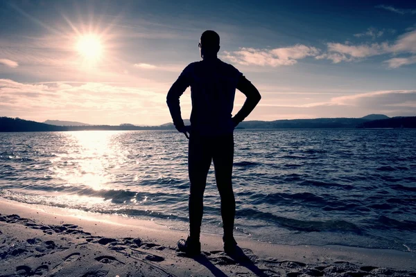 Silhouette of person in sportswear and short hair  on beach see into Sun above sea — Stock Photo, Image