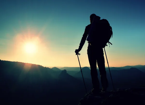 Silhouette nette d'un grand homme au sommet de la montagne avec soleil dans le cadre. Guide touristique en montagne — Photo