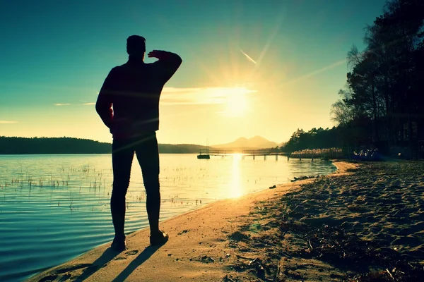 Tall man. Sunset above island and wharf  at coastline. Warm colors and hues of the rising sun — Stock Photo, Image