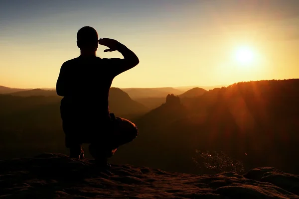 Ensam sportsman i svart. Tall vandrare i hukande ställning njuta utsikten i solnedgången på bergstopp — Stockfoto