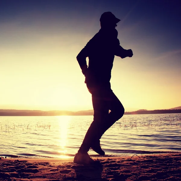 Coureur sur la plage. Sportsman courir dans casquette de baseball, jogging gars pendant le lever du soleil — Photo