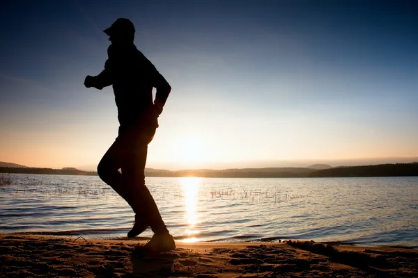 Lopende man op het strand. Sportman uitvoeren in honkbal GLB, joggen man tijdens de Sunrise periode — Stockfoto