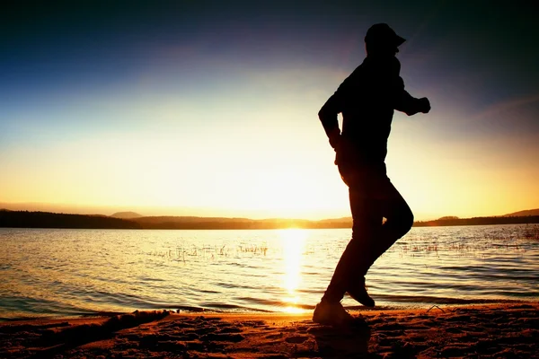 Running man on beach. Sportsman run in baseball cap, jogging guy during the sunrise — Stock Photo, Image