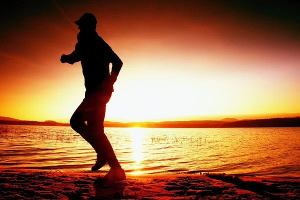 Τρέχοντας άτομο στην παραλία. Αθλητής τρέχει στο καπέλο του μπέιζμπολ, τζόκινγκ τύπος κατά την Ανατολή του ηλίου — Φωτογραφία Αρχείου