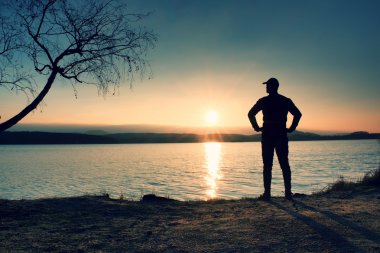 Uzun boylu Polonyalılar ve plajda sportif sırt çantası ile koyu spor giyim uzun yürüyüşe çıkan kimse zevk günbatımı ufuktan bulutlar ile mavi gökyüzü ile.