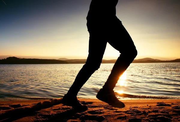 Silhouette of sport active man running and exercising on the beach at sunset. — Stock Photo, Image