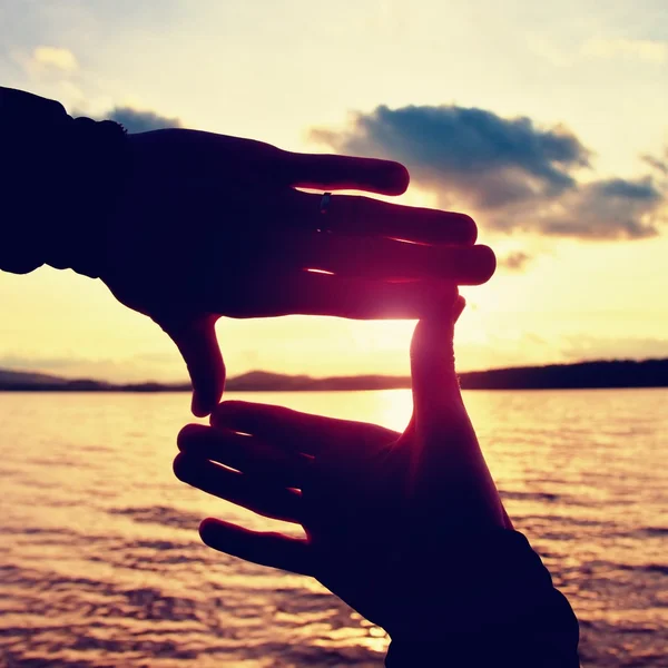 Tomadas de la mano en marco cuadrado con puesta de sol sumergida en el horizonte. Tarde de otoño en el lago . —  Fotos de Stock