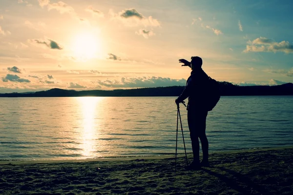 Homme debout près de la plage regardant le coucher du soleil, niveau d'eau paisible — Photo
