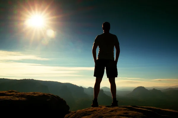 Alone hiker in black pants  stand on rock empire and watching over the misty and foggy morning valley to Sun. — Stock Photo, Image