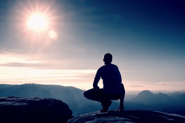 Alone hiker in black pants  stand on rock empire and watching over the misty and foggy morning valley to Sun. — Stock Photo, Image