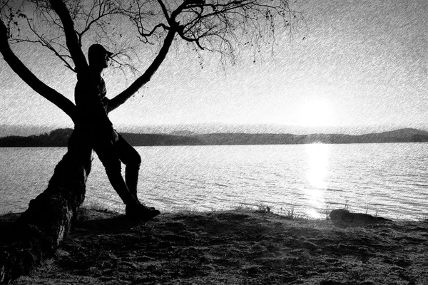 Esbozo retro rayado en blanco y negro. Hombre en el árbol. La silueta del hombre solitario se sienta en la rama del abedul en la orilla . — Foto de Stock