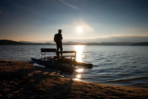 Turista alto con mochila a pie en la playa en barco a pedal en la puesta del sol. Otoño en el mar — Foto de Stock