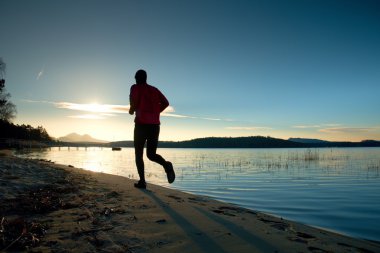 Çalışan adam. Erkek koşucu gündoğumu sırasında kumsalda koşu