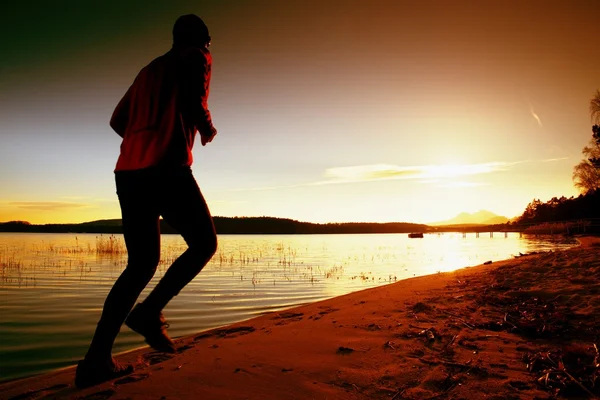 Sportieve Man doen ochtend joggen op zee strand van Bright Sunrise silhouetten — Stockfoto