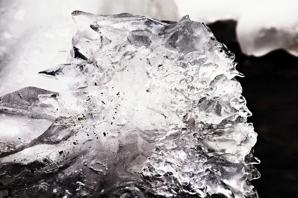 Beautiful big piece of ice with abstract cracks. Icicle bellow waterfall, stony and messy stream bank — Stock Photo, Image