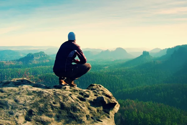 Resting man at the top of rock with aerial view of the deep misty valley bellow — Stock Photo, Image
