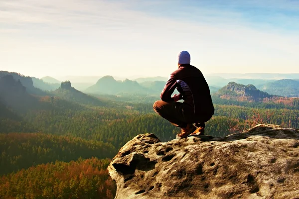 Resting man at the top of rock with aerial view of the deep misty valley bellow — Stock Photo, Image