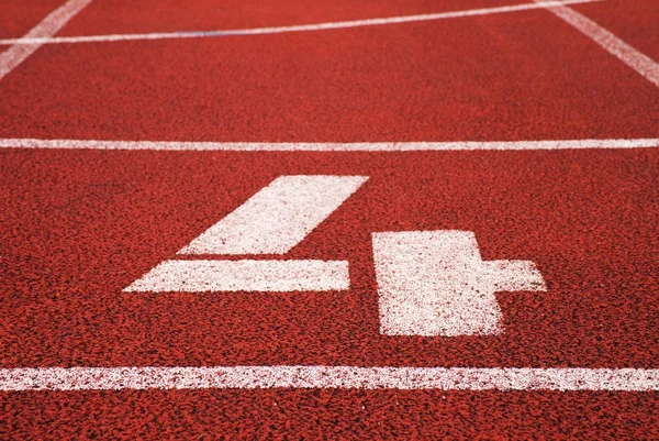 Número cuatro. Número de pista blanca en el circuito de caucho rojo, textura de las pistas de carreras en el estadio —  Fotos de Stock