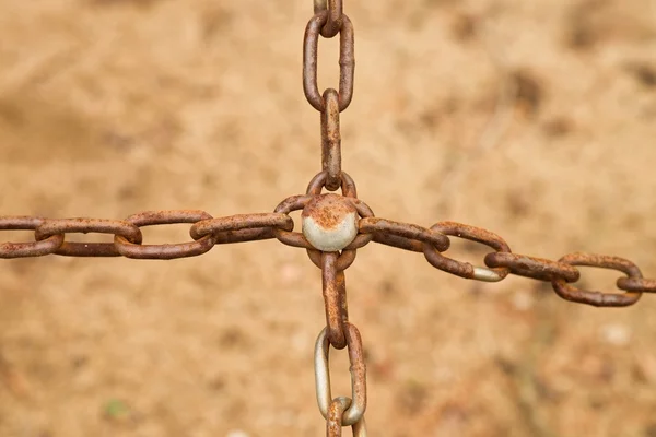 Joined old rusty chain in cross, close up view of chain and screw