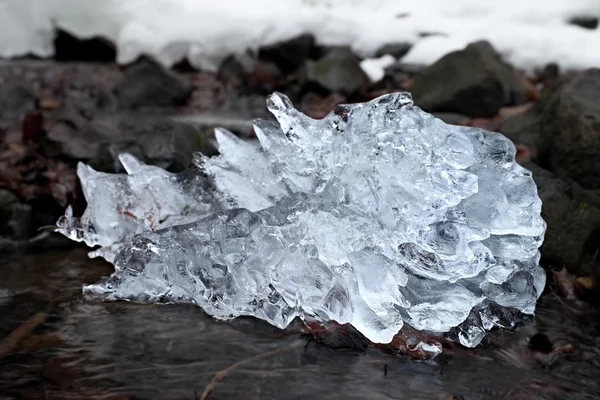 Hermoso pedazo grande de hielo con grietas abstractas. Icicle la cascada del fuelle, banco pedregoso y desordenado del arroyo —  Fotos de Stock