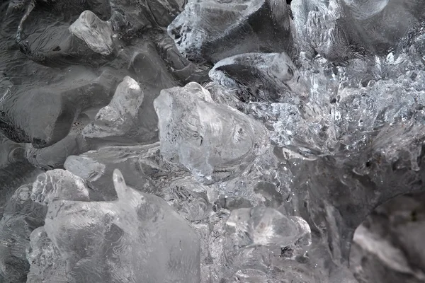 Beautiful big piece of ice with abstract cracks. Icicle bellow waterfall, stony and messy stream bank — Stock Photo, Image