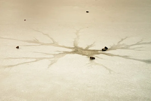 Sprickor och hål i is på dammen, dark ice i hålet och sten runt. — Stockfoto