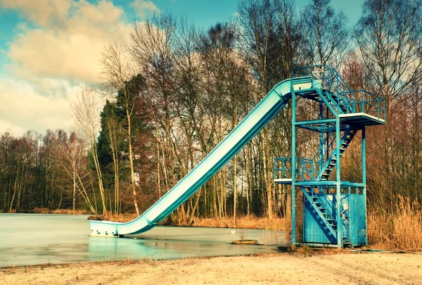 Old blue sliding track on lake beach, frozen watel level. Winter time — Stock Photo, Image