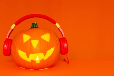 Mutlu oyulmuş balkabağı Cadılar Bayramı dekorasyon festivali ve müzik konsepti arka planda. Turuncu arka planda radyo dinleyen çeşitli balkabaklarını karıştır..