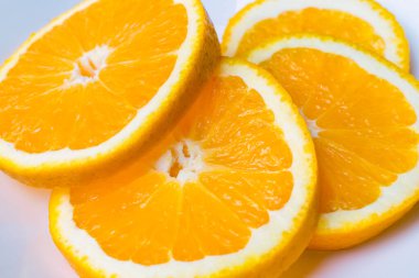 Beyaz bir tabakta dört taze, sulu portakal dilimi. Üst görünüm, resmi kapat