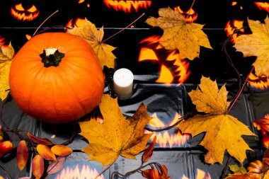 Sonbahar kompozisyonu. Balkabağı, mum, renkli arka planda kurumuş yapraklar. Sonbahar, sonbahar, Cadılar Bayramı konsepti. Düz konum, üst görünüm kopyalama alanı