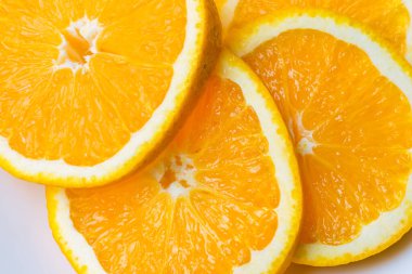 Beyaz bir tabakta dört taze, sulu portakal dilimi. Üst görünüm, resmi kapat