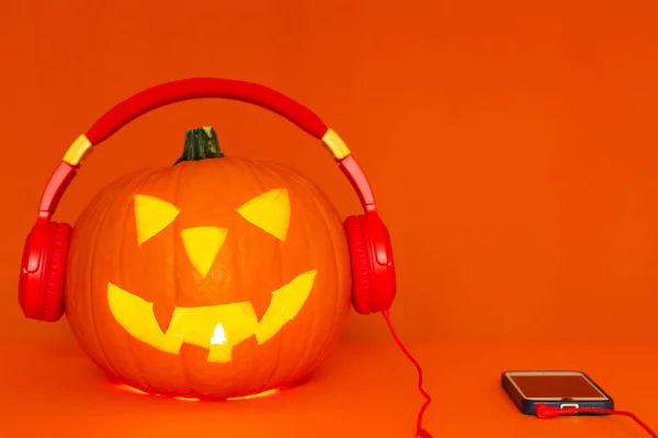 Happy carved pumpkin Halloween decorations festival and music concept background.Mix variety pumpkin listening radio by headphone on orange background.