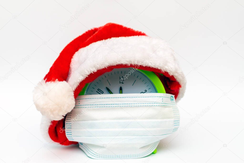 New Year alarm clock santa hat medical mask on white background countdown to midnight.Clock showing nearly 12.