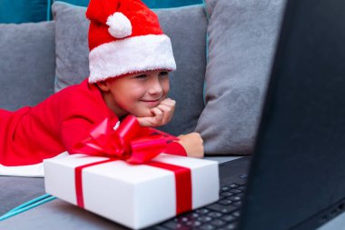 Uzanan çocuk, Noel 'i arkadaşlarıyla salgın sırasında yaptığı bir video görüşmesiyle karşılıyor. Yan bakış açısını kapat..