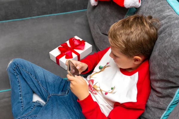 Zbliżenie Atrakcyjny Chłopiec Pomocą Smartfona Boże Narodzenie Biały Prezent Zdjęcia — Zdjęcie stockowe