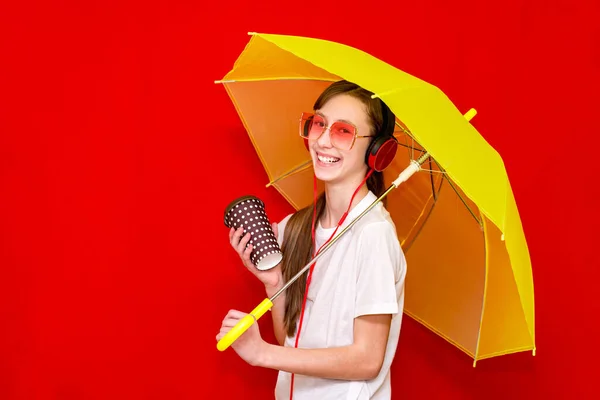 Nastolatka Słucha Muzyki Słuchawkach Parasolem Czerwony Studio Tło Noszenie Biały — Zdjęcie stockowe