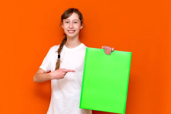 オレンジ色のスタジオの背景にバナー広告でフォルダを突いて驚くべき若い女の子 コピースペースバナー — ストック写真